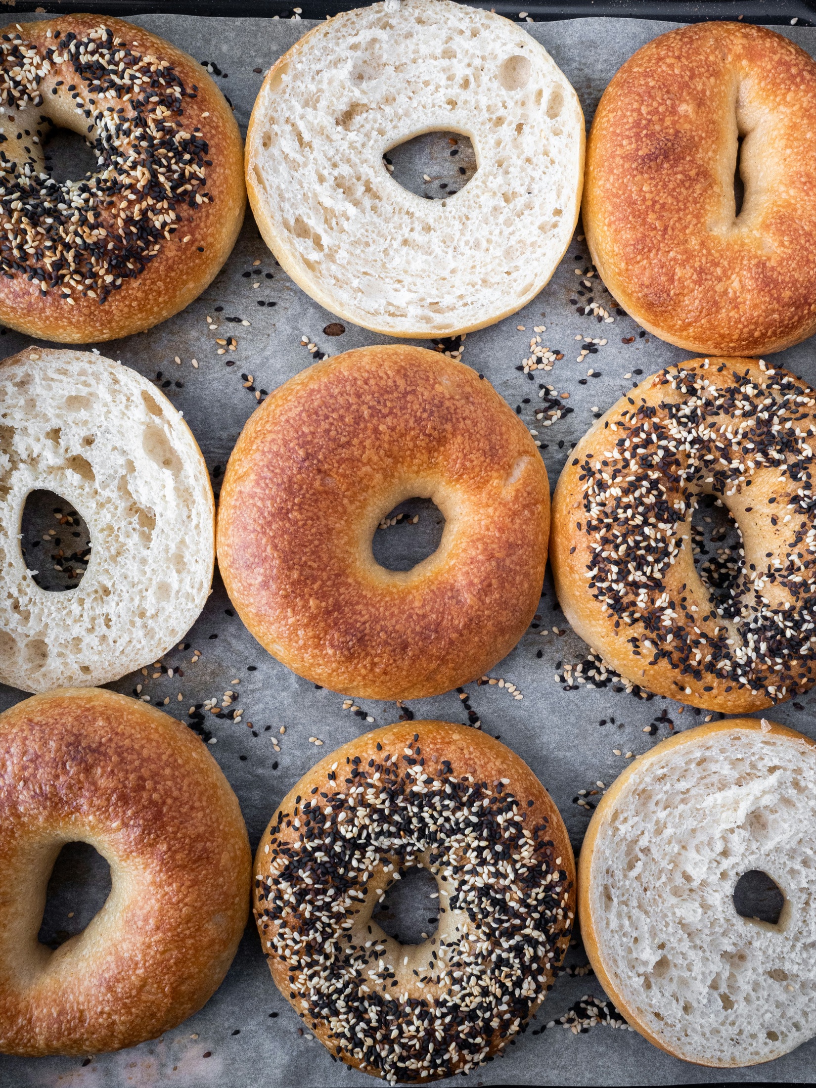 Fresh plain and everything bagels on a baking tray
