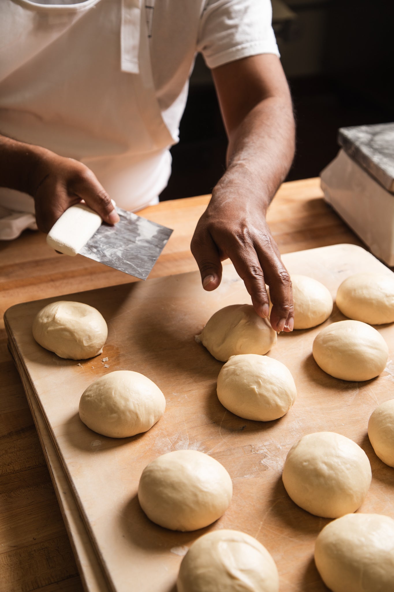 Baker shaping rounds of dough by hand